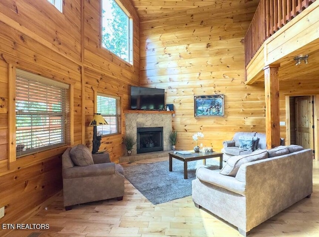 2205 Meredith Way, Sevierville, TN 37876 - living area with wood walls, a fireplace, a towering ceiling, and light wood-style floors
