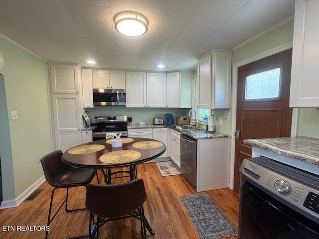 3207 Dove Ln, White Pine, TN 37890 - kitchen featuring stainless steel appliances, white cabinets, wood finished floors, crown molding, and light stone countertops