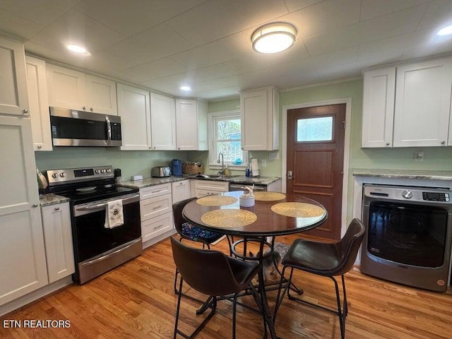 3207 Dove Ln, White Pine, TN 37890 - kitchen with stainless steel appliances, washer / dryer, white cabinets, and light wood-style flooring