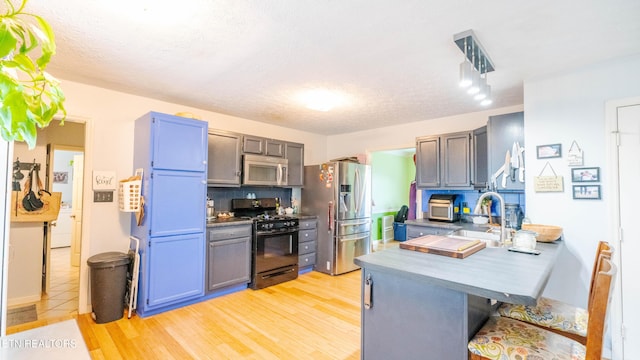 1517 Randal Park Dr, Knoxville, TN 37922 - kitchen with stainless steel appliances, a peninsula, a kitchen breakfast bar, backsplash, and light wood-type flooring