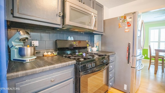 1517 Randal Park Dr, Knoxville, TN 37922 - kitchen featuring black gas stove, white microwave, decorative backsplash, freestanding refrigerator, and light wood-style flooring