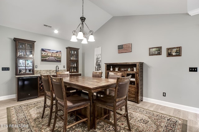 129 Dudi Trl, Vonore, TN 37885 - dining room featuring light wood-style floors, a chandelier, vaulted ceiling, and bar
