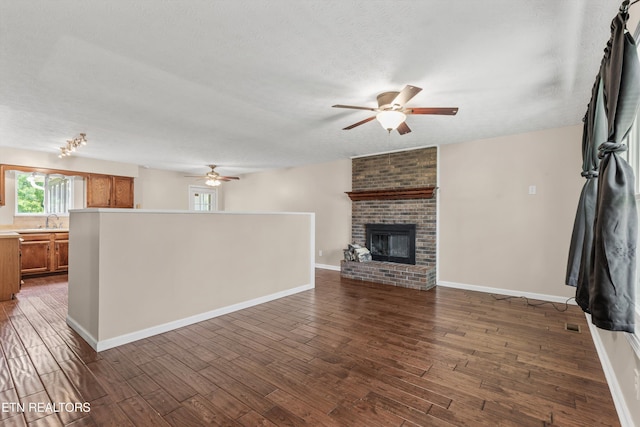 10609 Sprawls Pt, Knoxville, TN 37932 - unfurnished living room with a ceiling fan, dark wood-style floors, a brick fireplace, and a textured ceiling