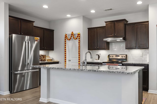 10703 Grantham Ln, Knoxville, TN 37932 - kitchen featuring appliances with stainless steel finishes, under cabinet range hood, dark brown cabinetry, light stone countertops, and recessed lighting