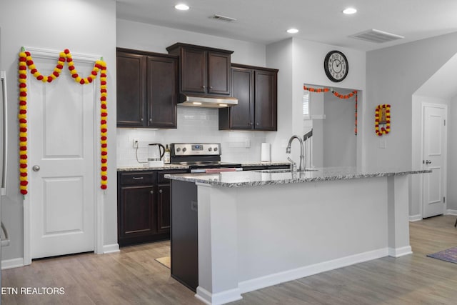 10703 Grantham Ln, Knoxville, TN 37932 - kitchen with electric range, under cabinet range hood, light stone counters, light wood-style floors, and recessed lighting