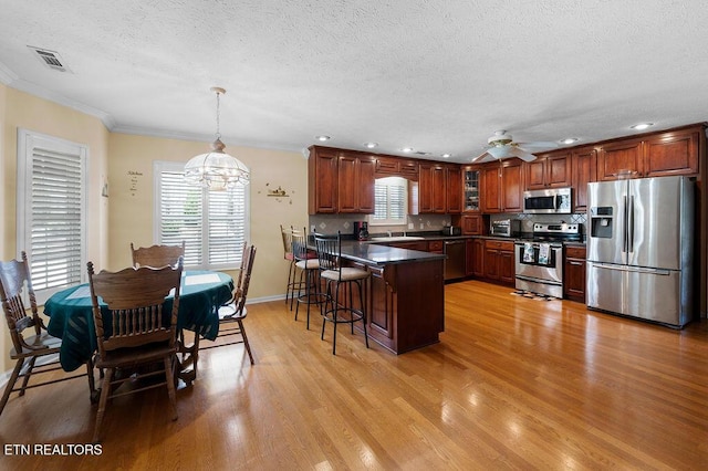 674 Southview Cir, Kodak, TN 37764 - kitchen with stainless steel appliances, a peninsula, a chandelier, dark countertops, and light wood finished floors