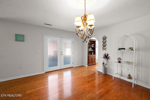 674 Southview Cir, Kodak, TN 37764 - spare room featuring a textured ceiling, french doors, wood finished floors, a chandelier, and arched walkways
