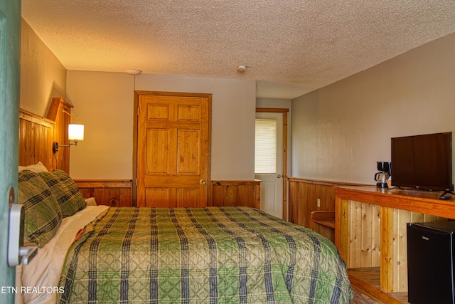 3636 Pickett Park Hwy, Jamestown, TN 38556 - bedroom with a wainscoted wall, a textured ceiling, black fridge, and wood finished floors