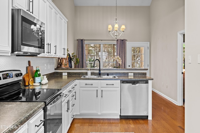 10867 Carpenter Run Ln Unit 44, Knoxville, TN 37932 - kitchen featuring stainless steel appliances, a towering ceiling, a chandelier, backsplash, and white cabinetry
