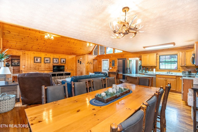 1507 Boo Boos Way, Sevierville, TN 37862 - dining room with a chandelier, vaulted ceiling, wooden walls, light wood-type flooring, and a textured ceiling