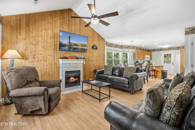 814 Plantation Dr, Pigeon Forge, TN 37863 - living area featuring vaulted ceiling, a ceiling fan, wooden walls, a tile fireplace, and light wood-style floors