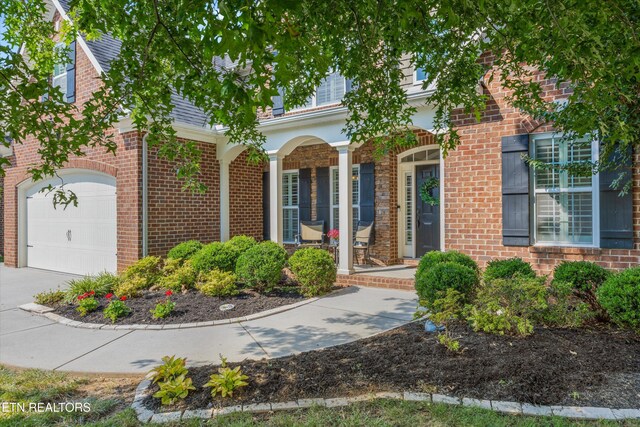 1213 Whisper Trace Ln, Knoxville, TN 37919 - view of front of home with covered porch, brick siding, concrete driveway, and a garage