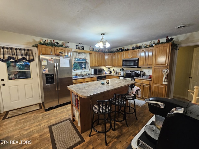 199 Pear Tree Way, Del Rio, TN 37727 - kitchen with appliances with stainless steel finishes, a chandelier, a kitchen island, wood finished floors, and a textured ceiling
