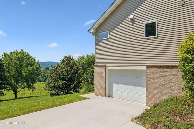 3930 Settlers Trl, Kodak, TN 37764 - view of side of home with concrete driveway, an attached garage, brick siding, and a yard