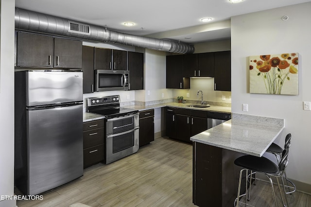 603 W Main St Unit 201, Knoxville, TN 37902 - kitchen with appliances with stainless steel finishes, a peninsula, light wood-type flooring, a breakfast bar, and light stone counters