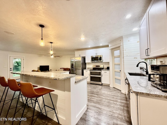 3402 Lillie Blvd, Sevierville, TN 37876 - kitchen with stainless steel appliances, a ceiling fan, a textured ceiling, a breakfast bar area, and white cabinets