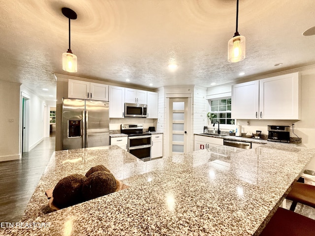 3402 Lillie Blvd, Sevierville, TN 37876 - kitchen with stainless steel appliances, white cabinets, recessed lighting, dark wood finished floors, and a breakfast bar area