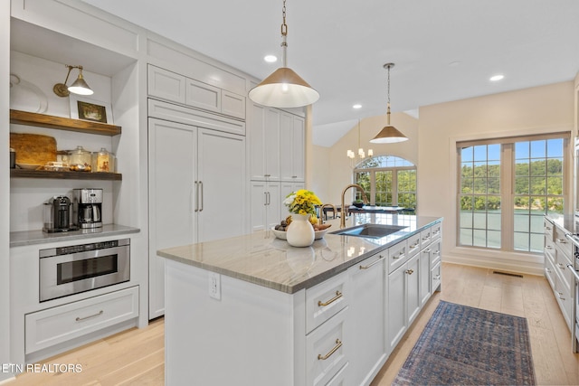 200 Stony Rock Ln, Jacksboro, TN 37757 - kitchen with light wood finished floors, a center island with sink, light stone countertops, paneled refrigerator, and open shelves