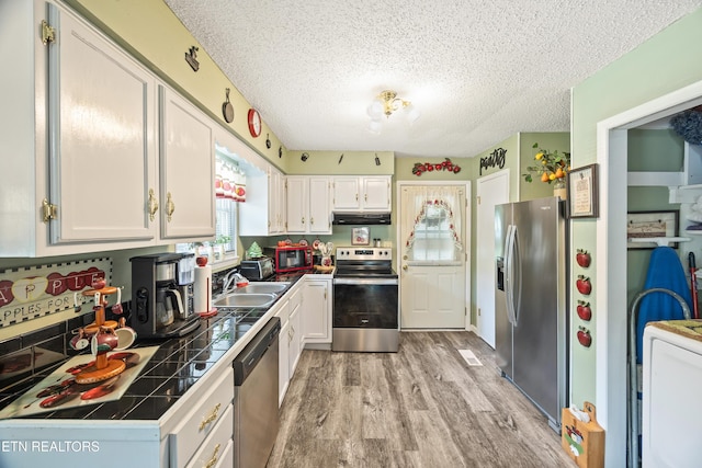 137 Jasper Dr, Crossville, TN 38558 - kitchen with appliances with stainless steel finishes, tile counters, under cabinet range hood, light wood-style floors, and a textured ceiling