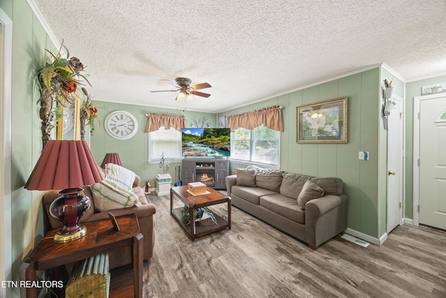 137 Jasper Dr, Crossville, TN 38558 - living room with crown molding, wood finished floors, ceiling fan, a textured ceiling, and a lit fireplace