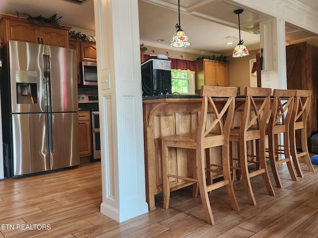 5412 E Lamar Alex Pkwy, Walland, TN 37886 - kitchen with stainless steel appliances, crown molding, light wood-style flooring, brown cabinetry, and hanging light fixtures