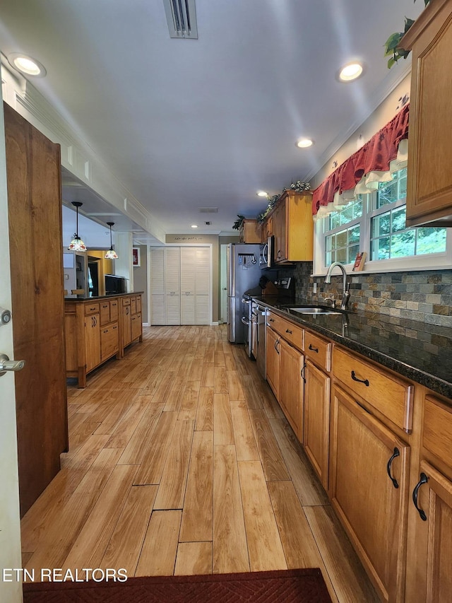 5412 E Lamar Alex Pkwy, Walland, TN 37886 - kitchen with light wood-style flooring, brown cabinets, decorative backsplash, dark stone counters, and appliances with stainless steel finishes