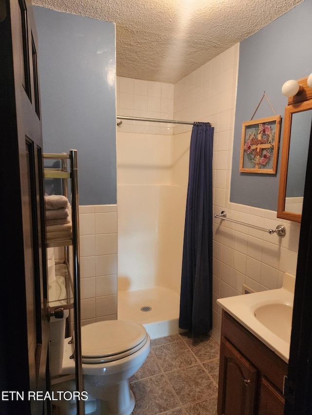 5412 E Lamar Alex Pkwy, Walland, TN 37886 - full bathroom featuring tile walls, a textured ceiling, a stall shower, vanity, and tile patterned floors