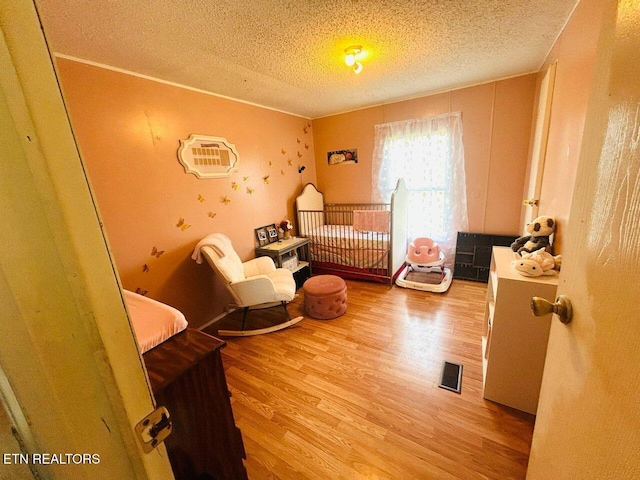181 Claude Hargis Ln, Crawford, TN 38554 - bedroom featuring wood finished floors, a textured ceiling, and a crib
