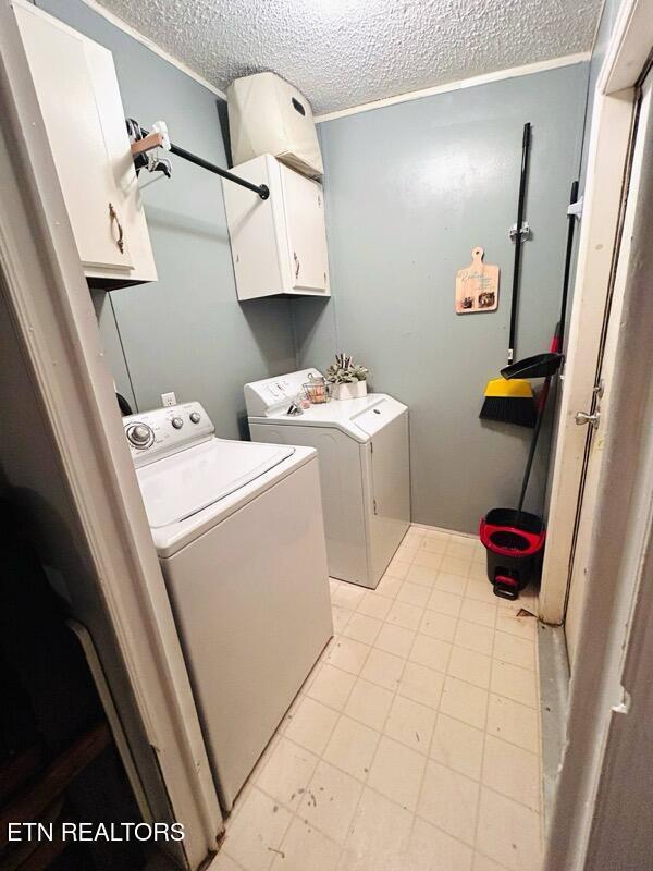 181 Claude Hargis Ln, Crawford, TN 38554 - laundry area featuring washing machine and clothes dryer, cabinet space, and a textured ceiling