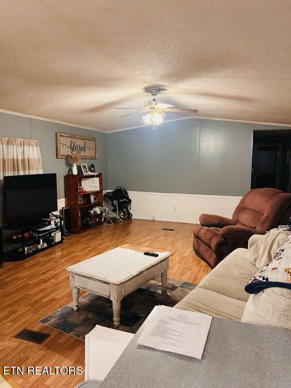 181 Claude Hargis Ln, Crawford, TN 38554 - living room featuring ceiling fan, a textured ceiling, wood finished floors, and crown molding