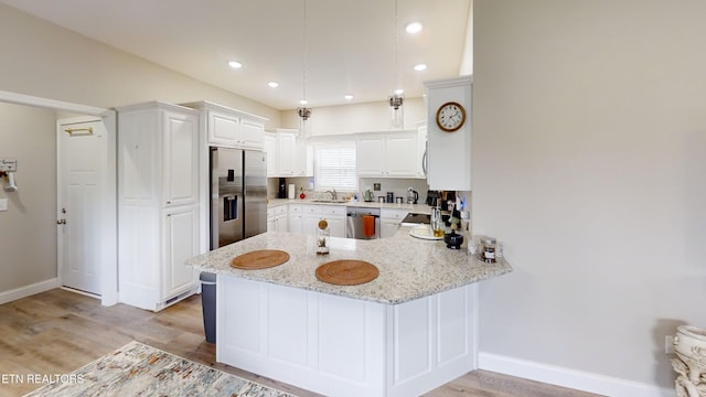 101 Maca Ridge Cir, Clarkrange, TN 38553 - kitchen featuring appliances with stainless steel finishes, light wood-style floors, a peninsula, light stone counters, and white cabinetry