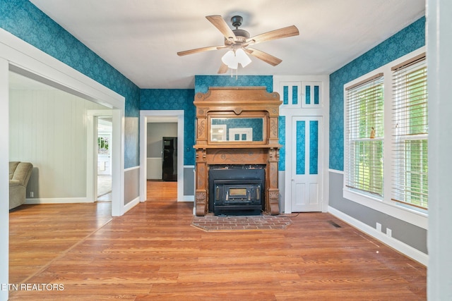 2115 Aaron Ct, Sevierville, TN 37876 - unfurnished living room featuring a wood stove, light wood-style flooring, ceiling fan, and wallpapered walls