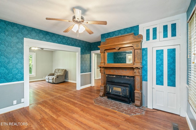 2115 Aaron Ct, Sevierville, TN 37876 - unfurnished living room with a wood stove, wood finished floors, ceiling fan, and wallpapered walls
