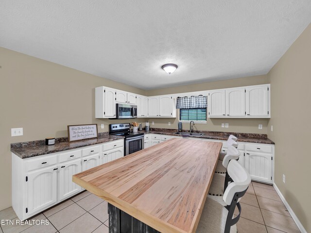 1371 Elijah Martin Rd, Whitesburg, TN 37891 - kitchen featuring stainless steel appliances, light tile patterned floors, dark countertops, white cabinetry, and a textured ceiling