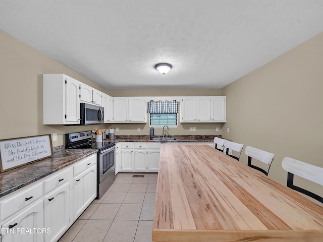 1371 Elijah Martin Rd, Whitesburg, TN 37891 - kitchen with stainless steel appliances, white cabinets, light tile patterned floors, dark stone counters, and a textured ceiling