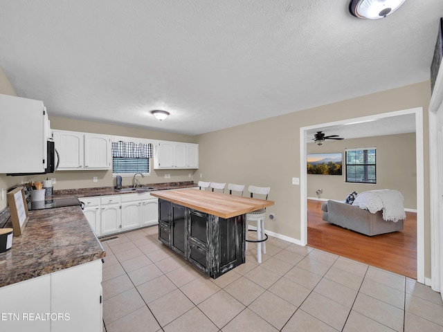 1371 Elijah Martin Rd, Whitesburg, TN 37891 - kitchen featuring white cabinets, light tile patterned floors, butcher block counters, a breakfast bar, and ceiling fan