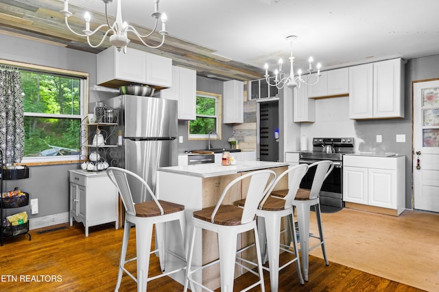 816 Thorn Grove Pike, Strawberry Plains, TN 37871 - kitchen featuring stainless steel appliances, a chandelier, white cabinets, wood finished floors, and a kitchen island