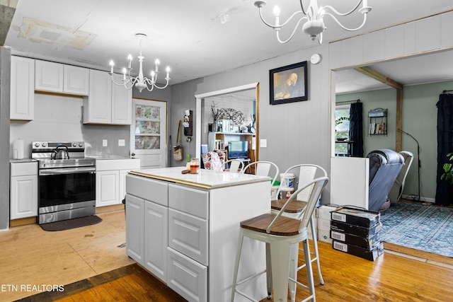 816 Thorn Grove Pike, Strawberry Plains, TN 37871 - kitchen featuring stainless steel electric range, a chandelier, white cabinetry, light wood finished floors, and light countertops