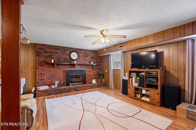 116 Oak St, Jacksboro, TN 37757 - living area with a textured ceiling, a ceiling fan, wood finished floors, wooden walls, and a fireplace