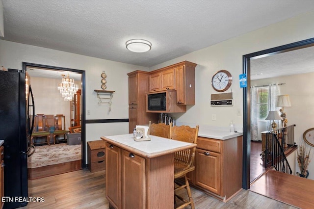 116 Oak St, Jacksboro, TN 37757 - kitchen with black appliances, light wood-type flooring, brown cabinets, light countertops, and a textured ceiling