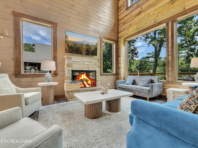 1940 Smoky Cove Rd, Sevierville, TN 37876 - living area featuring wood walls, a towering ceiling, an outdoor stone fireplace, plenty of natural light, and wood finished floors