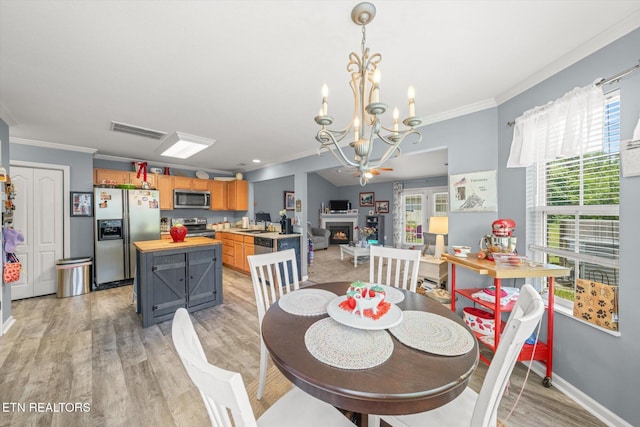 3701 Eliza Pointe Way, Knoxville, TN 37921 - dining area featuring crown molding, a chandelier, light wood-style floors, and a warm lit fireplace