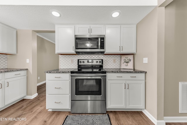 8707 Olde Colony Trl Unit 13, Knoxville, TN 37923 - kitchen featuring appliances with stainless steel finishes, light wood-style flooring, white cabinets, decorative backsplash, and dark stone counters