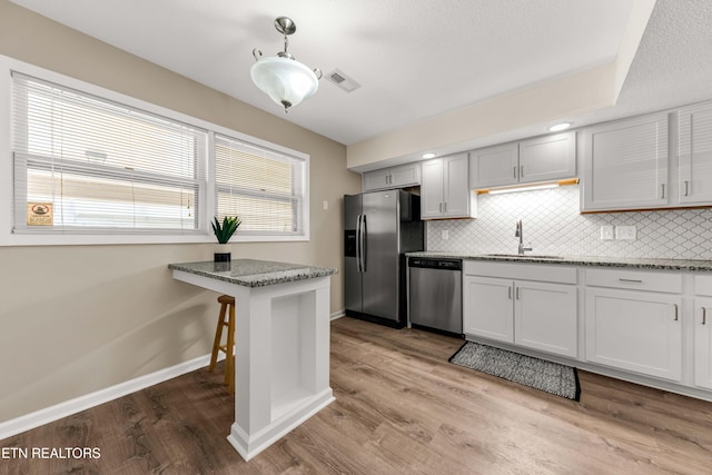 8707 Olde Colony Trl Unit 13, Knoxville, TN 37923 - kitchen featuring appliances with stainless steel finishes, decorative backsplash, wood finished floors, and light stone countertops