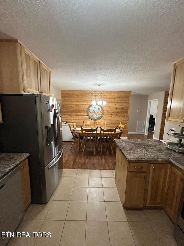 935 Pinetree Rd, Jamestown, TN 38556 - kitchen with stainless steel fridge, wooden walls, a peninsula, light tile patterned floors, and dark stone counters
