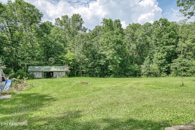 90 Byers Ln, Crossville, TN 38571 - view of green lawn featuring a forest view, an outdoor structure, and an outbuilding