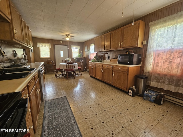 1106 Smyth Chapel Rd, Pennington Gap, VA 24277 - kitchen with black appliances, a ceiling fan, brown cabinets, light countertops, and wood walls