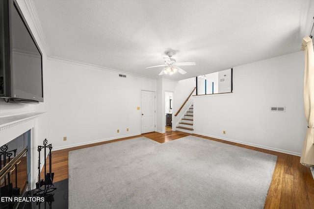 1476 Pheasants Glen Dr, Knoxville, TN 37923 - unfurnished living room with wood finished floors, a ceiling fan, stairs, ornamental molding, and a fireplace with flush hearth