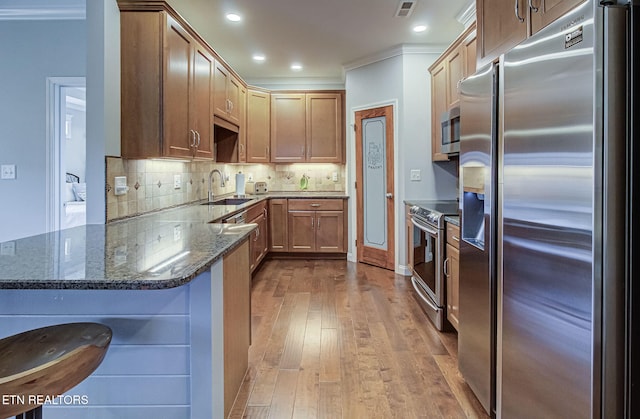 12504 Tangle Crest Ln, Knoxville, TN 37932 - kitchen featuring appliances with stainless steel finishes, dark stone counters, a peninsula, dark wood-style flooring, and tasteful backsplash