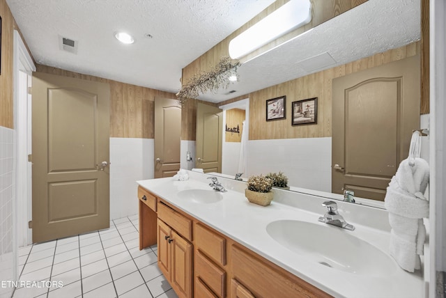 818 Golf View Blvd Unit 1502, Pigeon Forge, TN 37863 - bathroom featuring tile walls, double vanity, a textured ceiling, tile patterned flooring, and a wainscoted wall